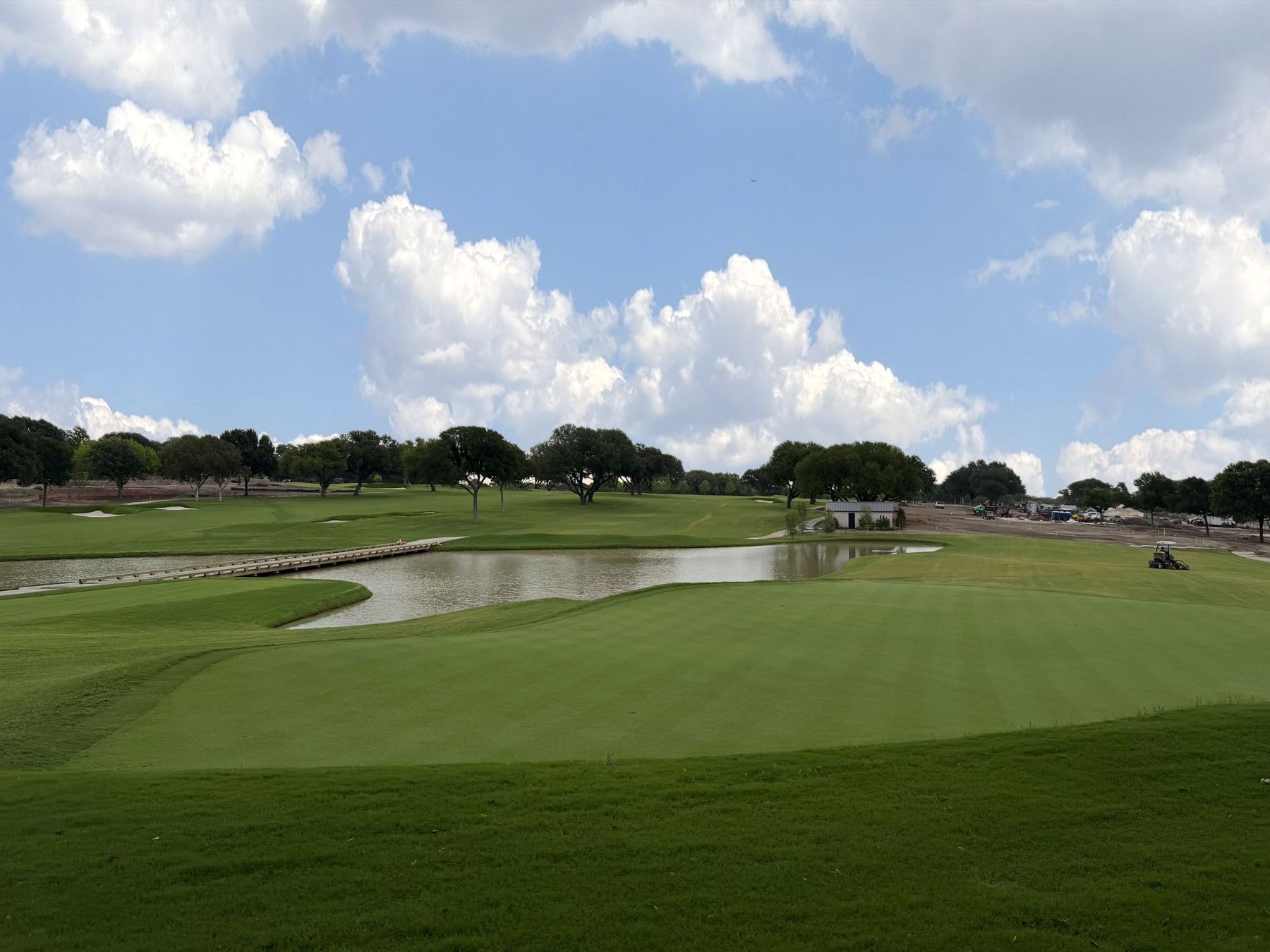 Bermuda fairway and green beside a pond under a blue sky