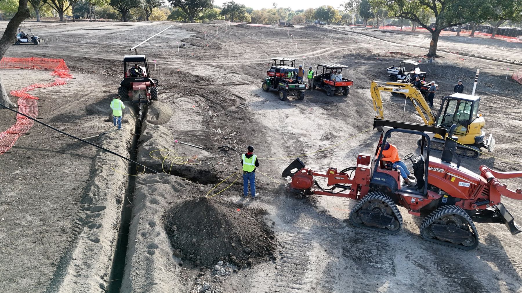 Crew trenching irrigation mainline across a golf course renovation
